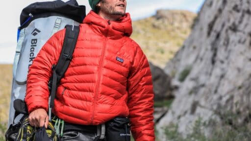 man looking above carrying gray patagonia backpack