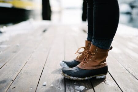 military person wearing brown-and-black leather LL bean boots standing on brown wooden dock