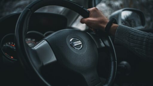 person holding black nissan steering wheel