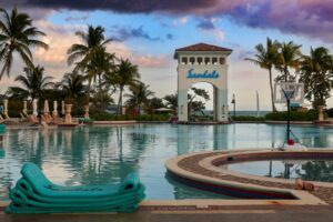 a large sandals swimming pool with a clock tower in the background