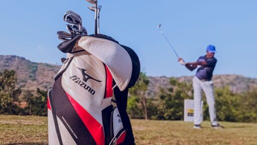 Mizuno Golf bag and player swinging under the clear blue sky on an Abuja course.