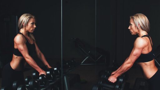 woman in equinox fitness club gym looking in mirror