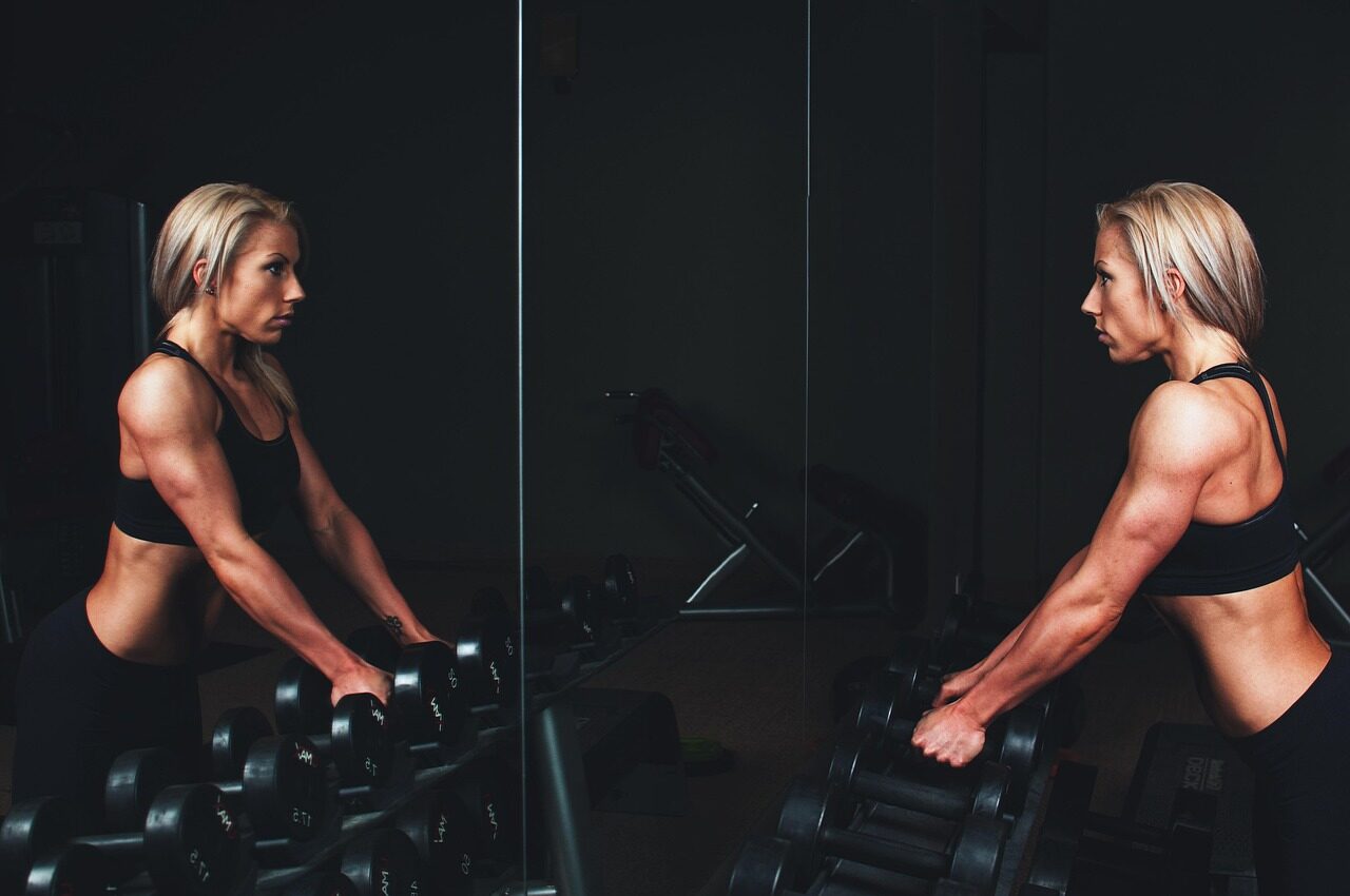 woman in equinox fitness club gym looking in mirror