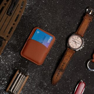 a watch, wallet, and other leather goods on a table