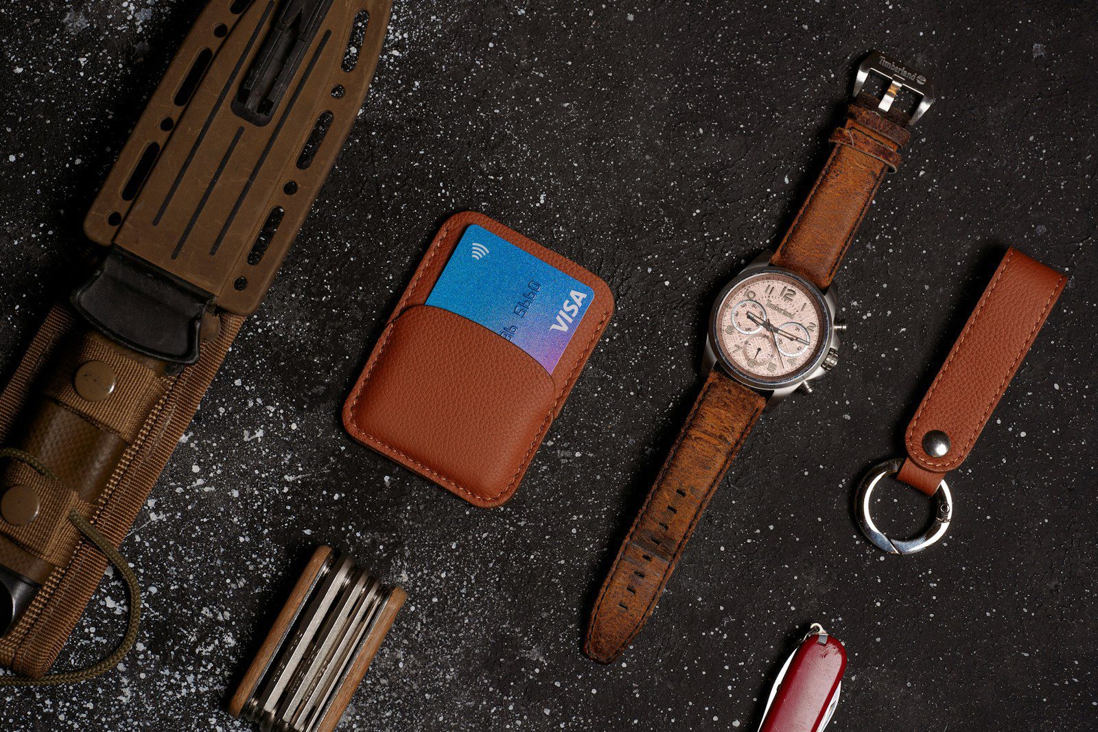 a watch, wallet, and other leather goods on a table