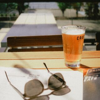 a glass of craft beer sitting on top of a table at the market