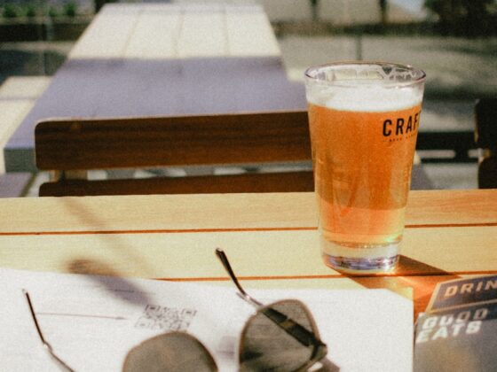 a glass of craft beer sitting on top of a table at the market