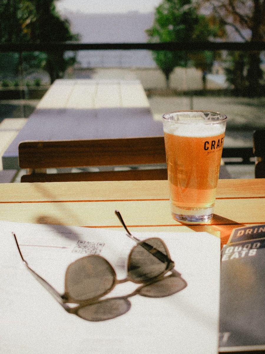 a glass of craft beer sitting on top of a table at the market