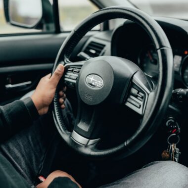 person holding black subaru steering wheel