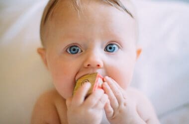 selective focus photography of baby holding wooden cube from baby depot