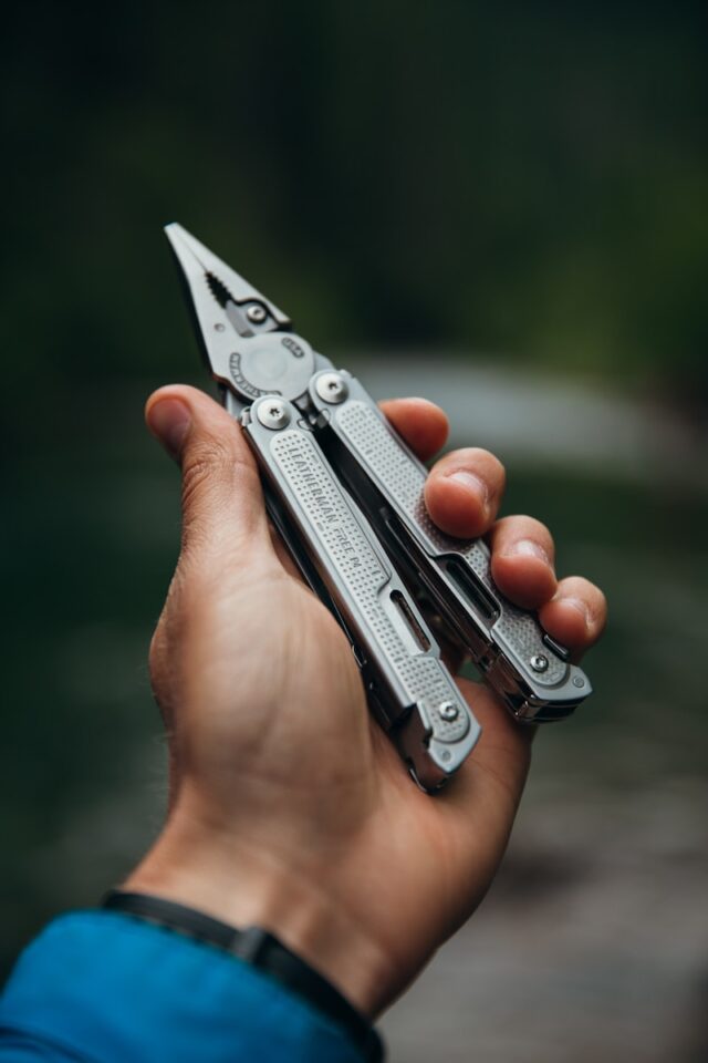 a person holding a leatherman multitool in their hand